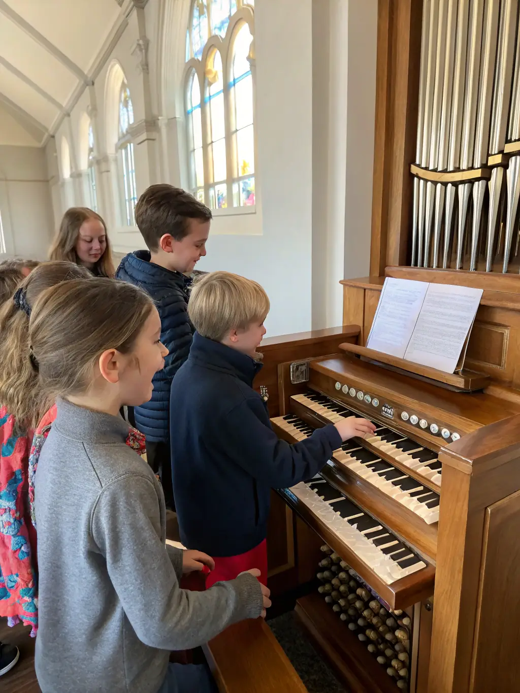 A photo of children participating in a music workshop, learning about the organ and its history, with instructors guiding them.